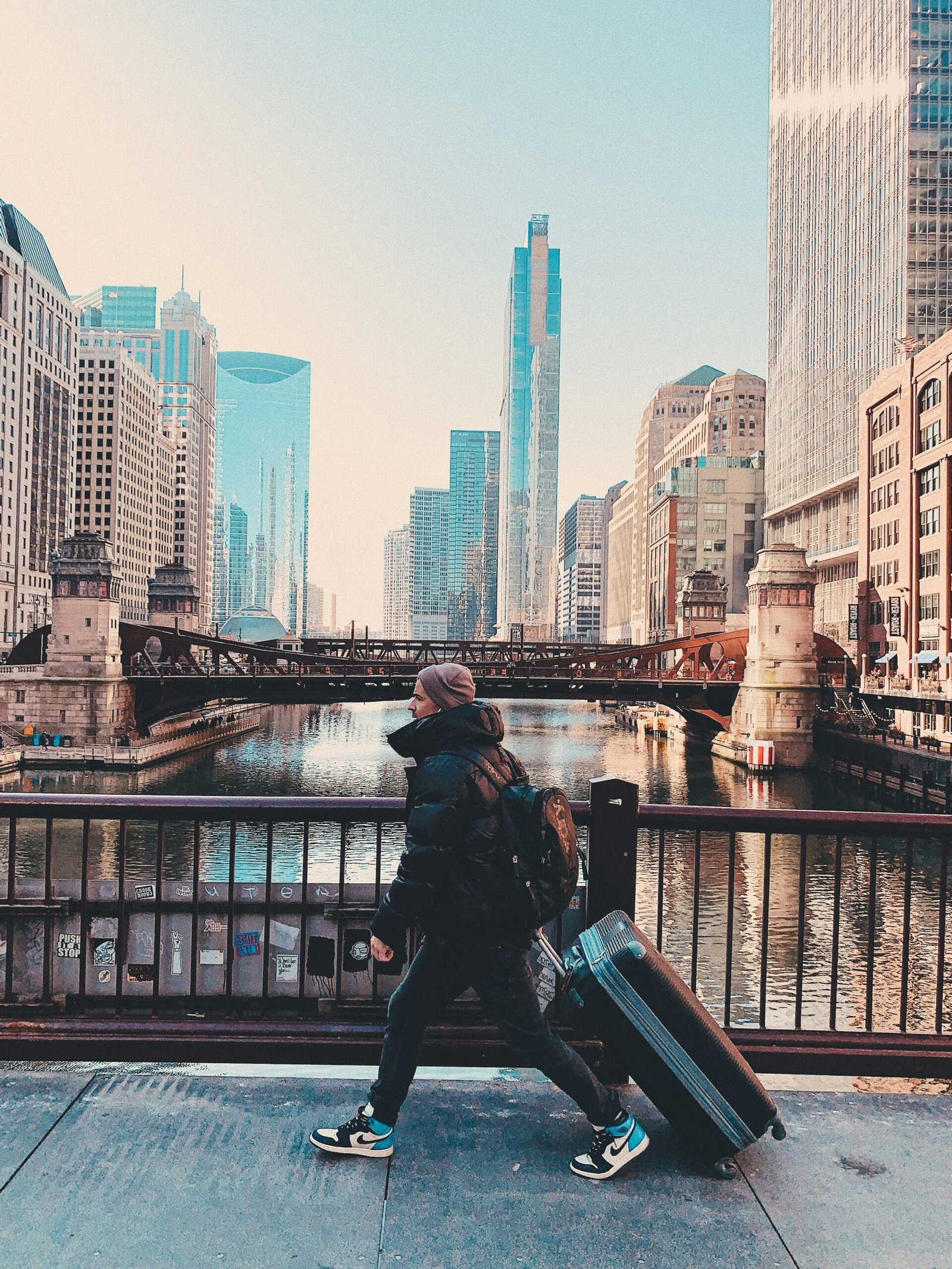 man in black jacket sitting on black metal railings near body of water during daytime